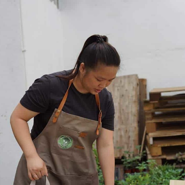 Sonia Gan from Mighty Greens gardening in brown leather apron